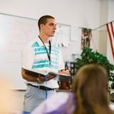 High school teacher standing and talking in front of the class.